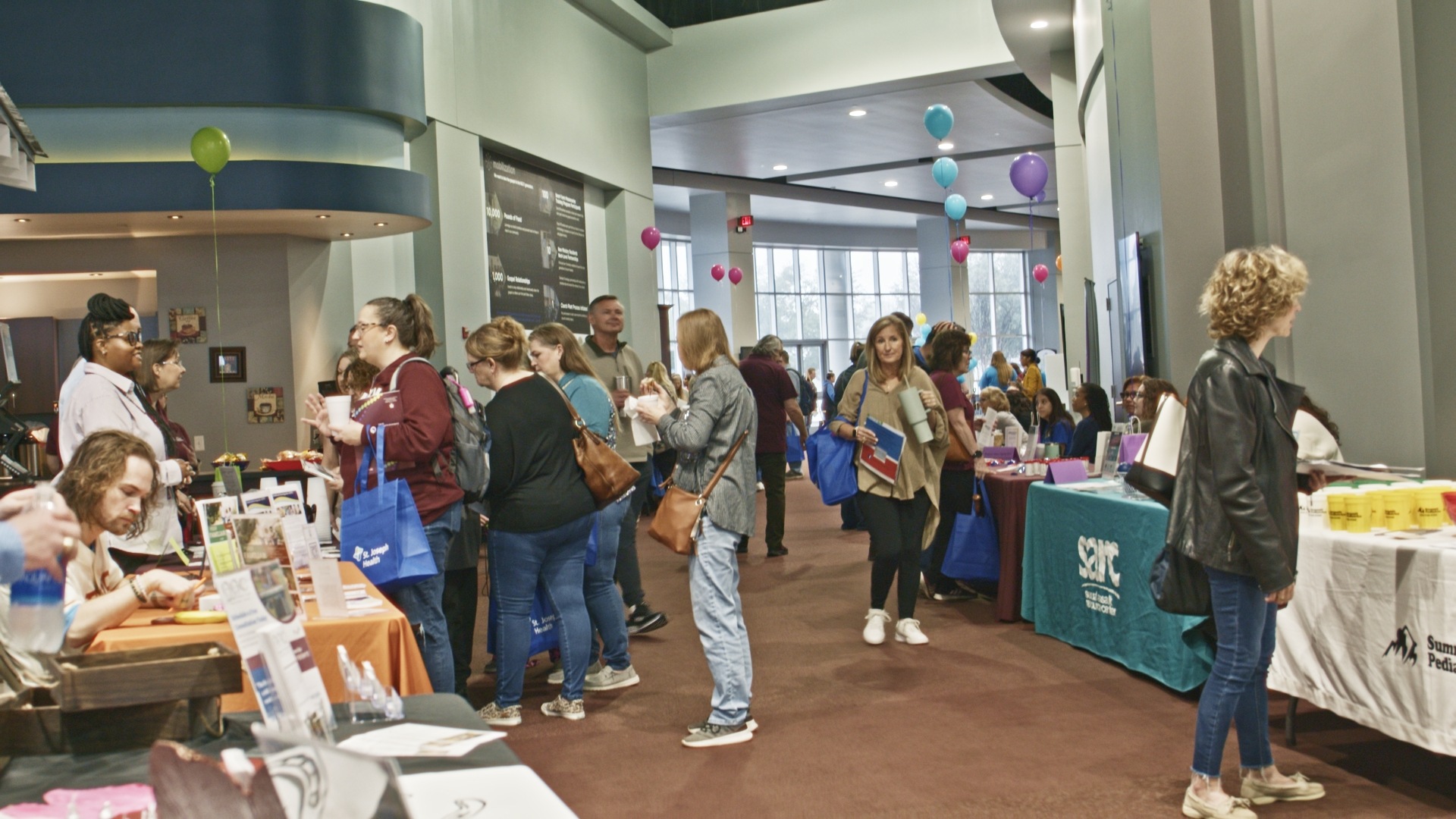 A photo of attendees at a conference visiting with vendors at tables.