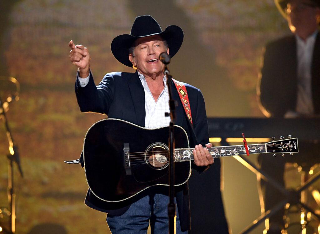 A photo of a singer with a guitar on stage during a concert.