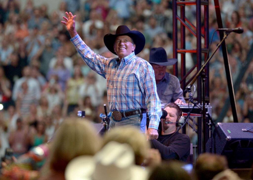 A photo of a singer waving to the crowd from the stage during a concert.