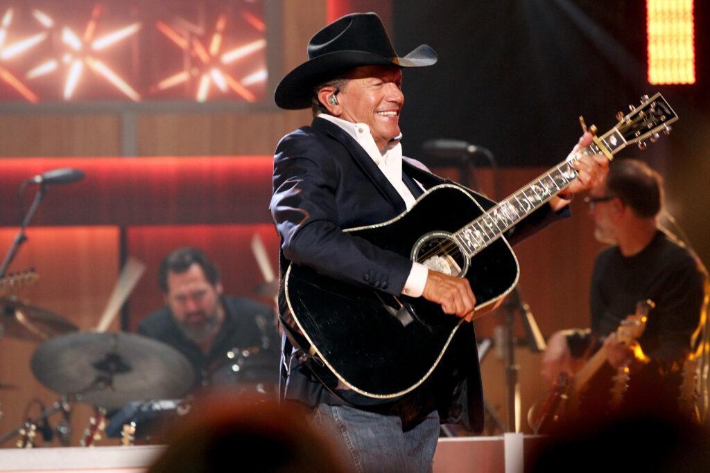 A photo of a singer on stage with a guitar during a performance.