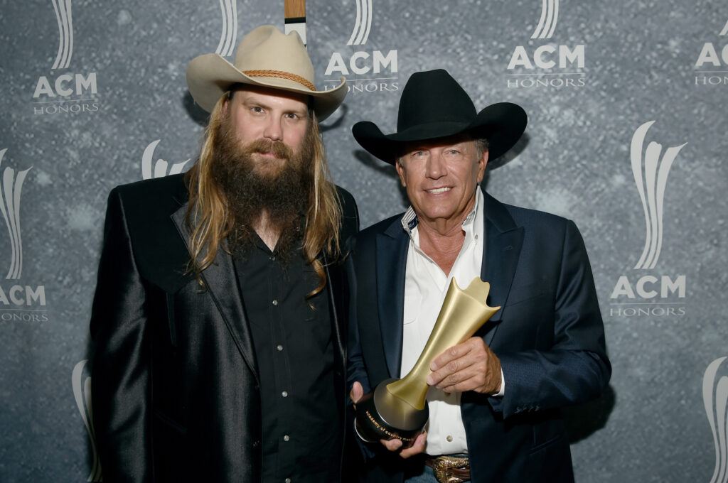 A photo of two country singers, with one of them holding an award.