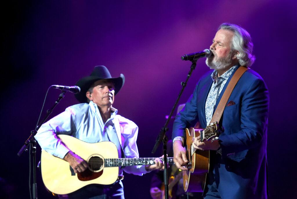 Two singers on a stage with guitars.