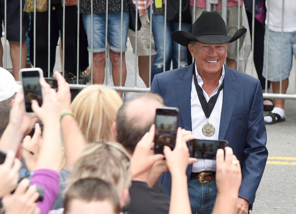 A photo of fans taking pictures of George Strait with phone cameras.
