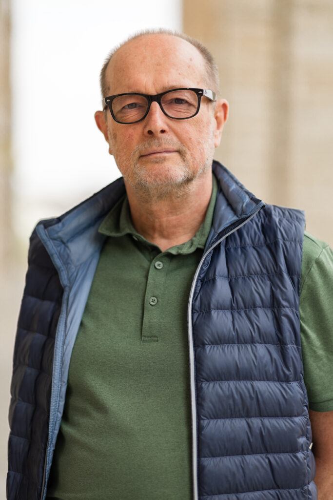 A photo of a man wearing glasses standing outside.