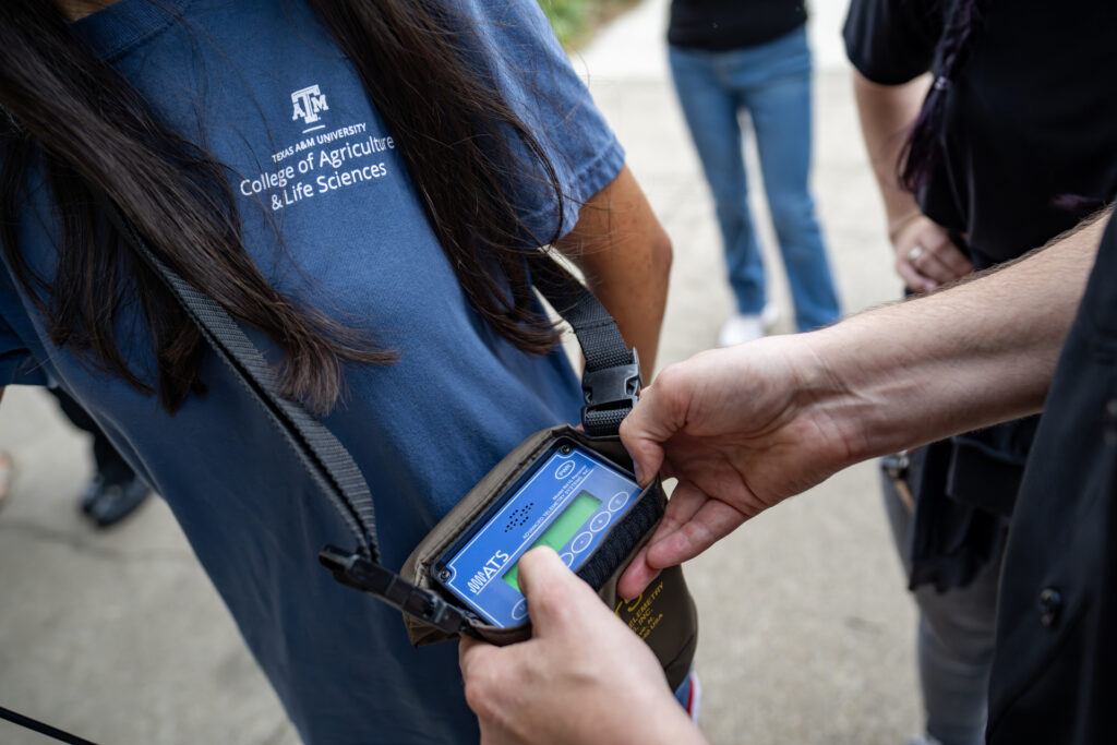 A man (Ty Werdel, Ph.D., assistant professor in the Texas A&M University Department of Rangeland, Wildlife and Fisheries Management) helps students with radio frequency gear