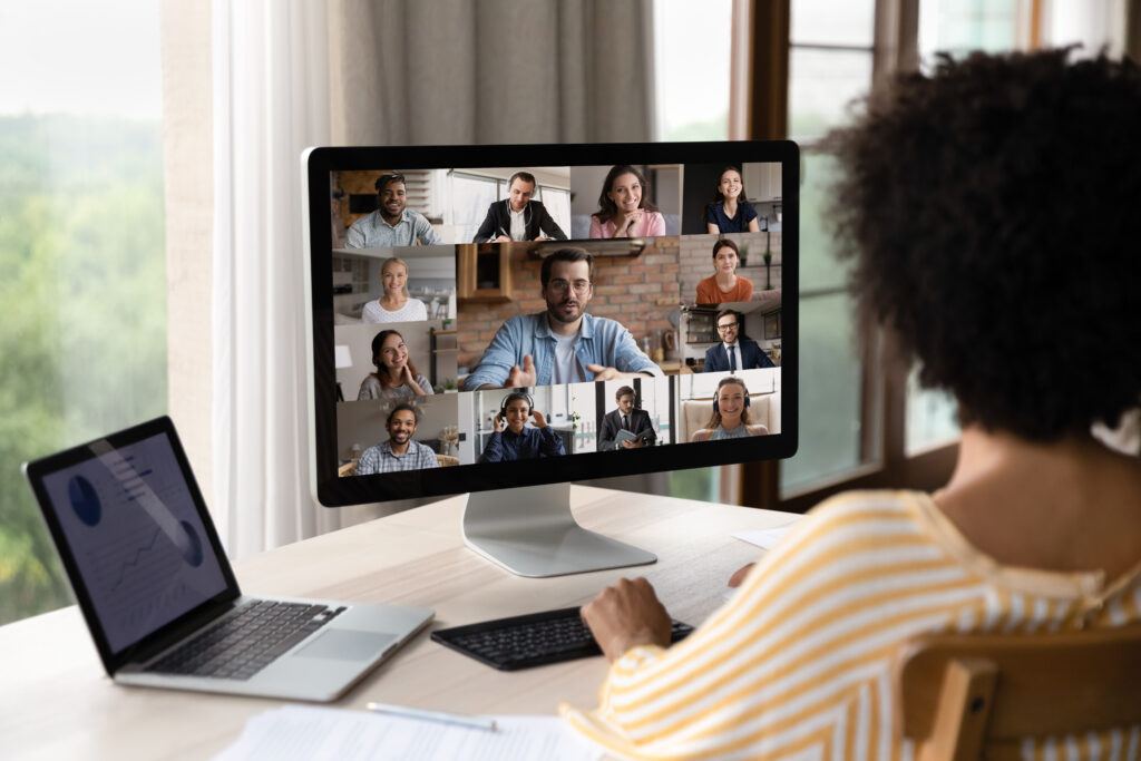 A remote worker looking at computer monitor while holding a video conference call with teammates.