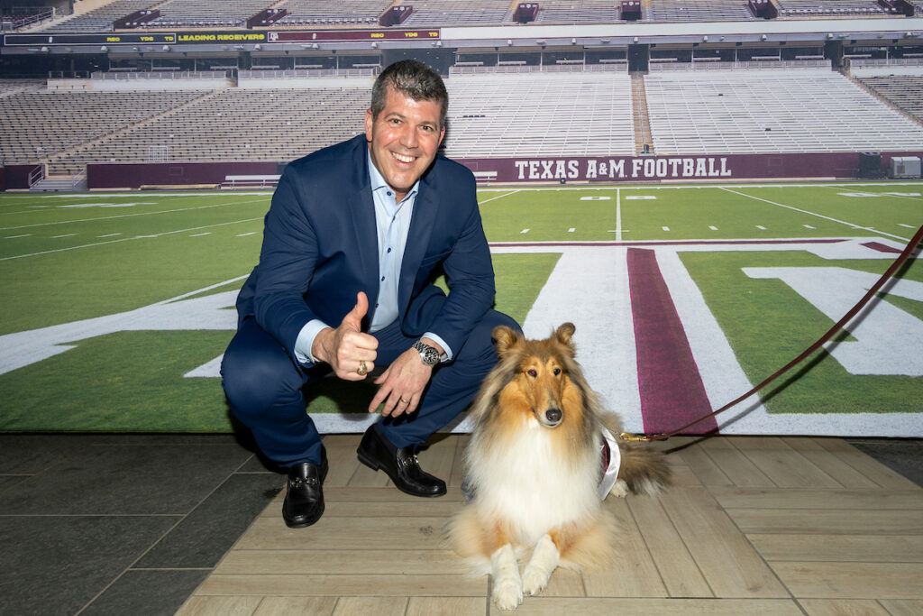 Fernando Palomo poses with Reveille X in front of a Kyle Field backdrop at the afterparty