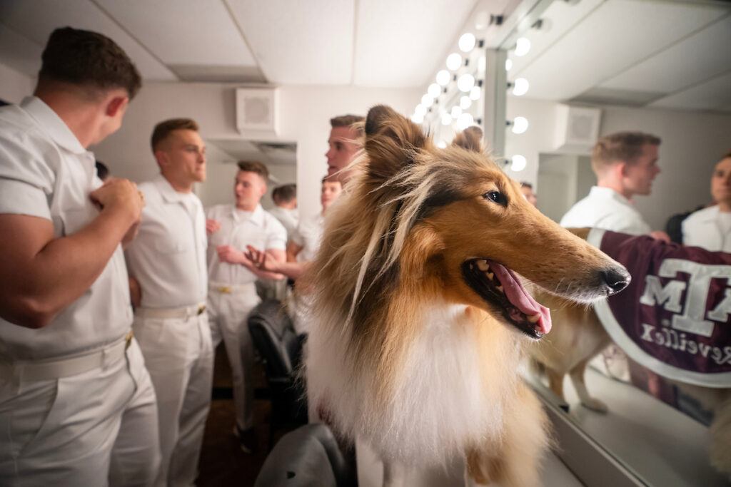 Reveille X checks herself out in the dressing room mirror, the Yell Leaders behind her