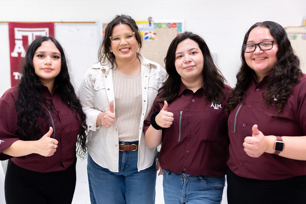 volunteers at the fair giving a Gig 'em thumbs up