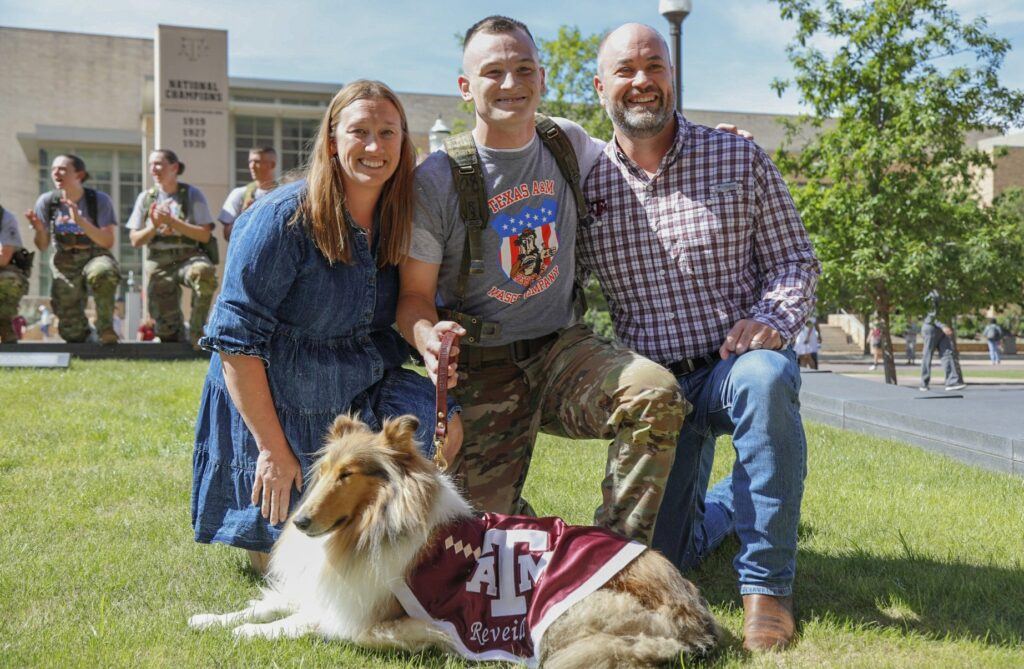 A cadet kneeling along with his parents with Reveille X on the Texas A&M University campus.