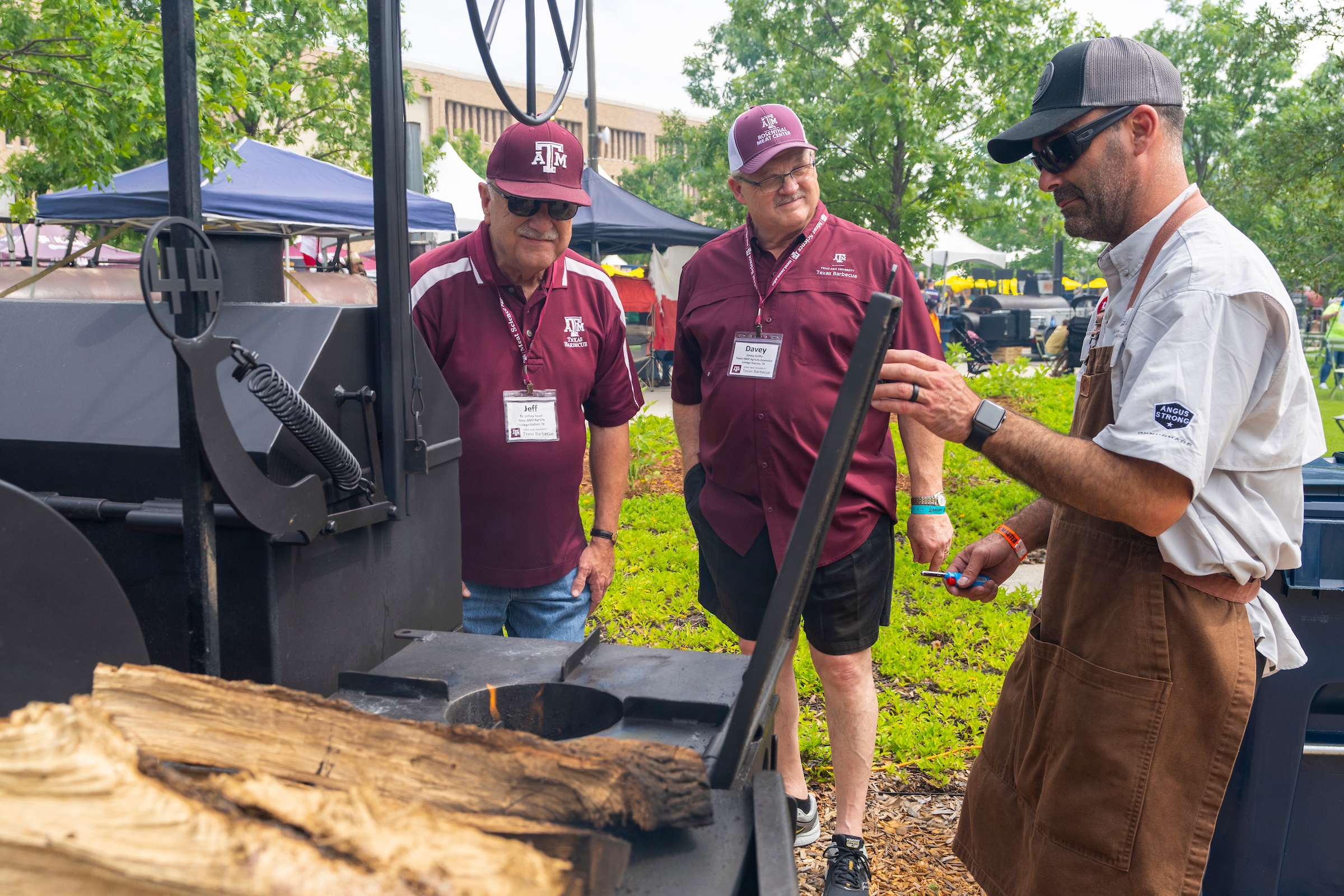 Three men around a barbecue pit.