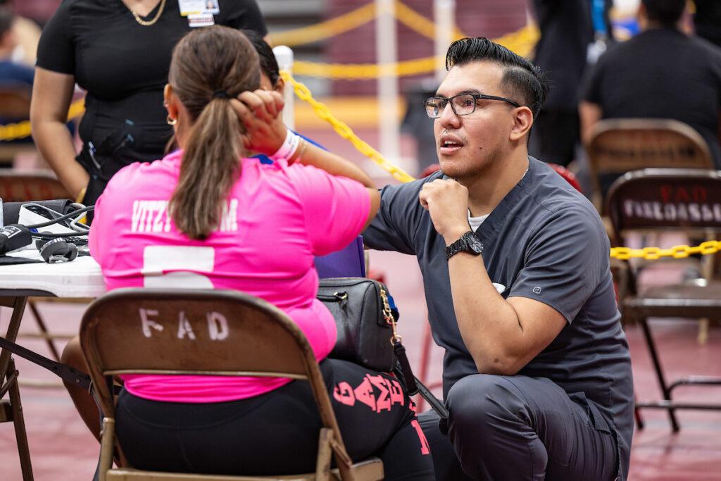 A volunteer listens to a patient's needs at PSJA Early College High School in Pharr, Texas on Thursday, July 27, 2023.