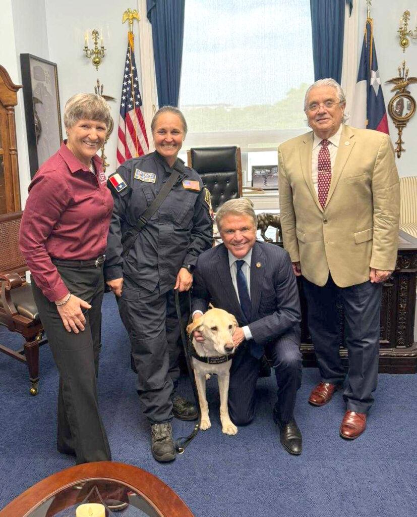Three people and a U.S. congressman in the congressman's Washington, D.C., office posing for a photo with a search and rescue dog.