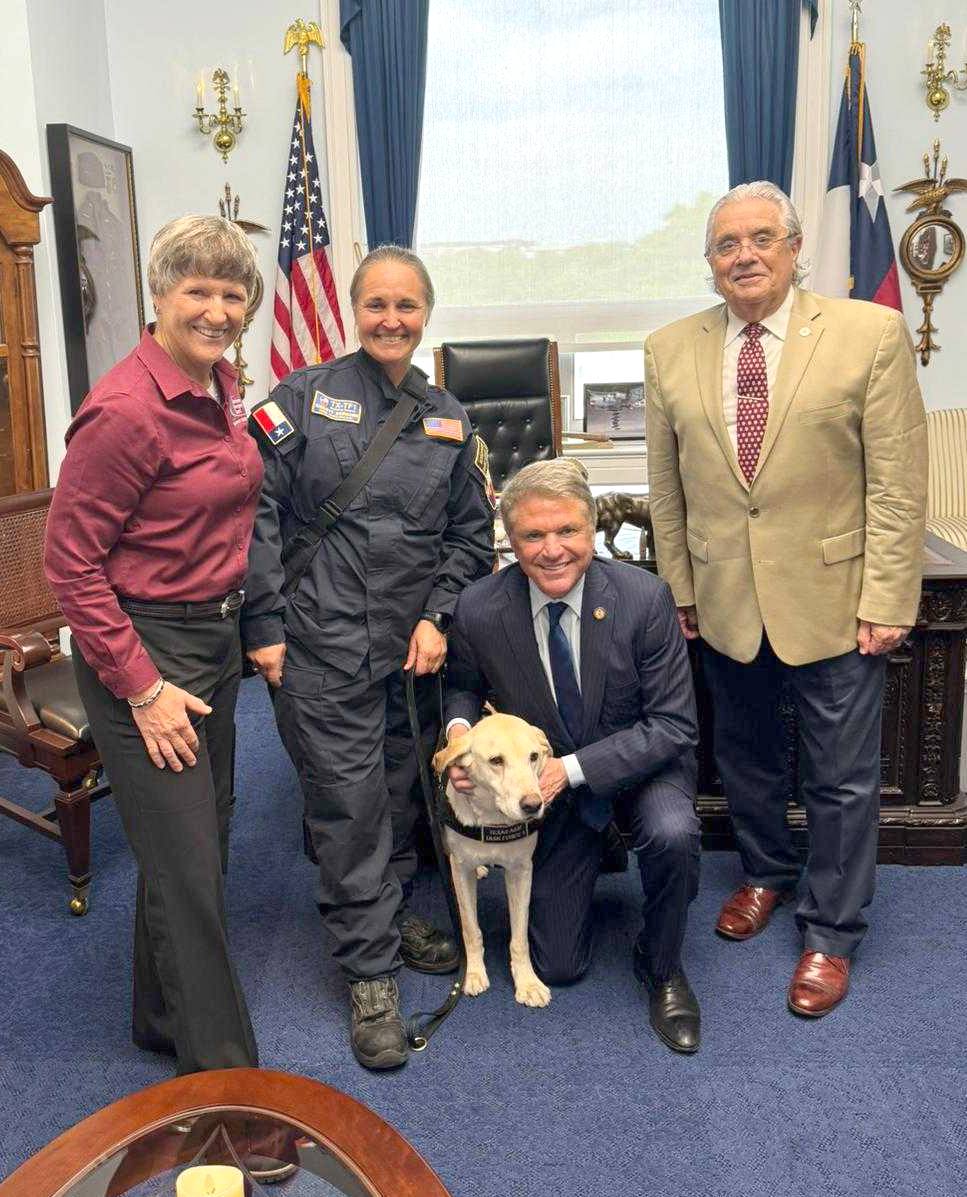 Three people and a U.S. congressman in the congressman's Washington, D.C., office posing for a photo with a search and rescue dog.