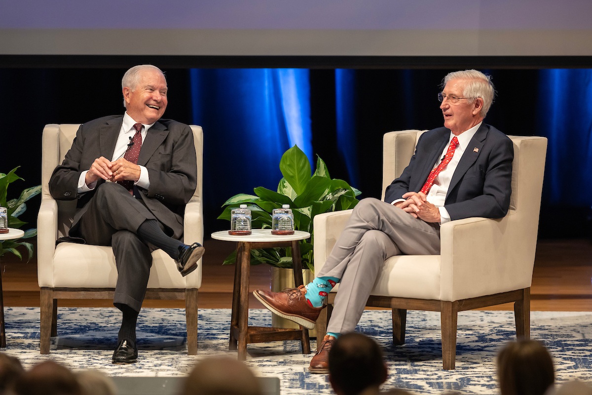 Robert Gates and Andrew Card seated on stage during a panel.