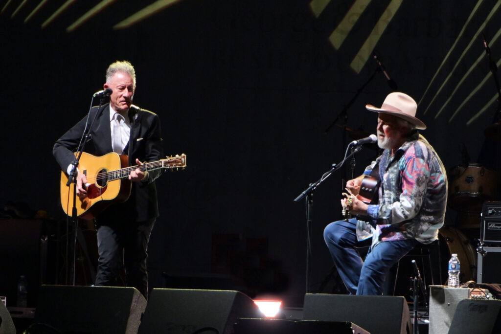 Musicians Lyle Lovett and Robert Earl Keen perform on stage.