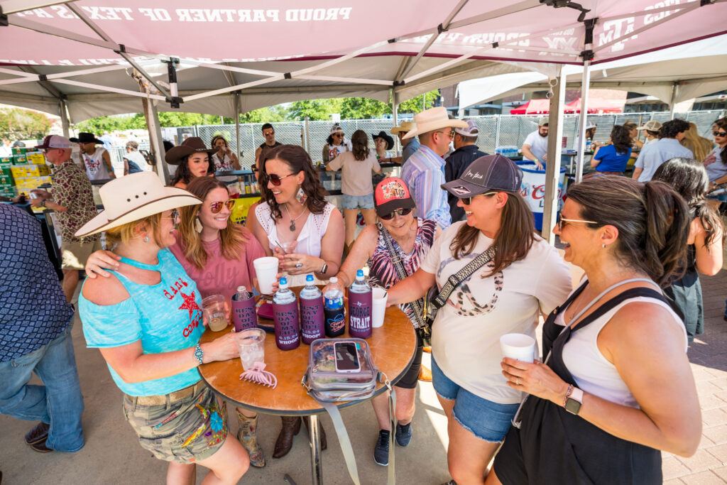 Fans gather around a table outside Kyle Field prior to a George Strait concert.