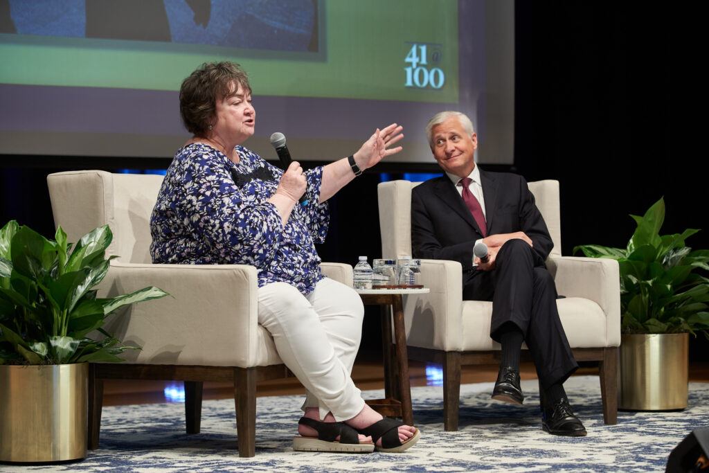 Authors Jean Becker and Jon Meacham speak from chairs on a stage at an event.