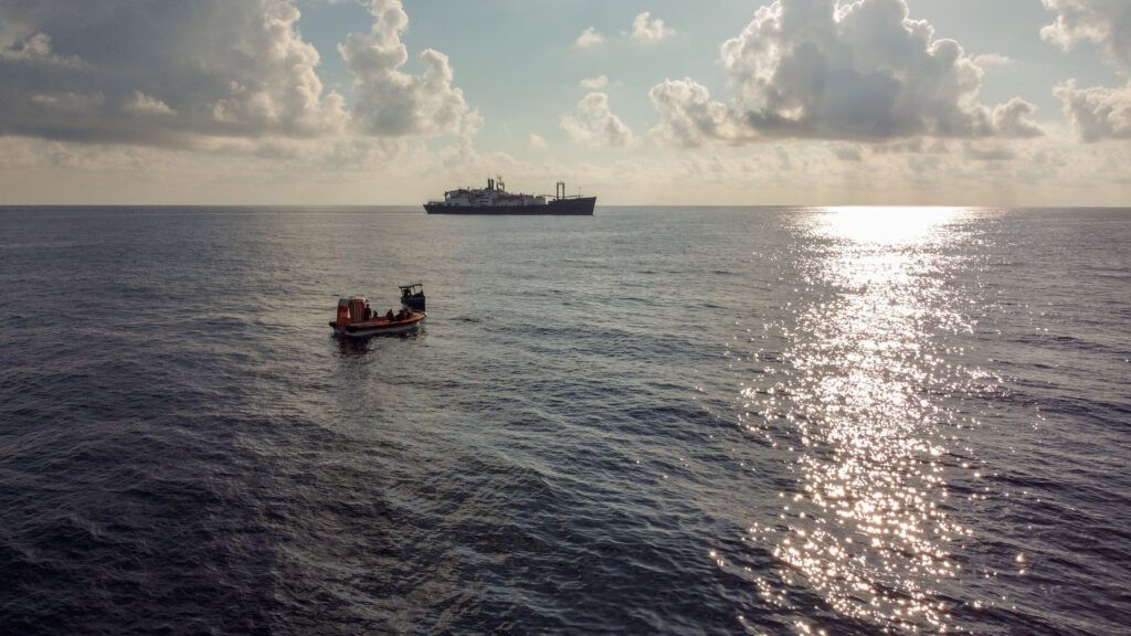 A photo of a small boat with a ship in the background in the Gulf of Mexico.