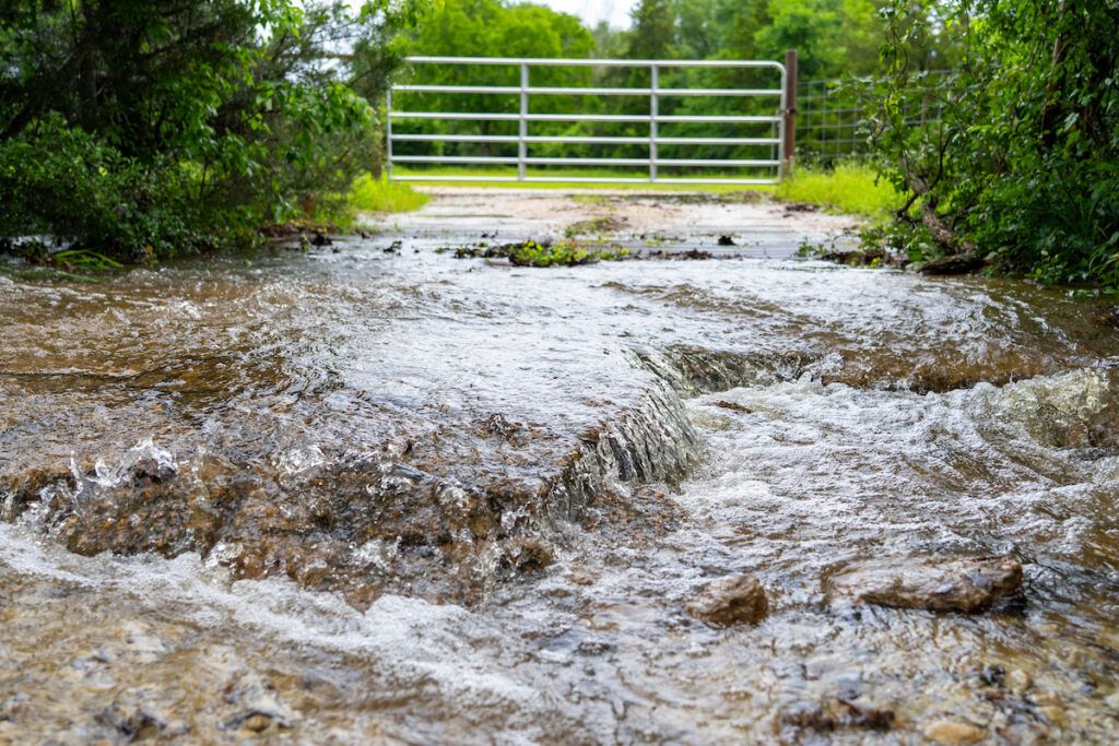 Water runs downhill over rocks outside a gated area