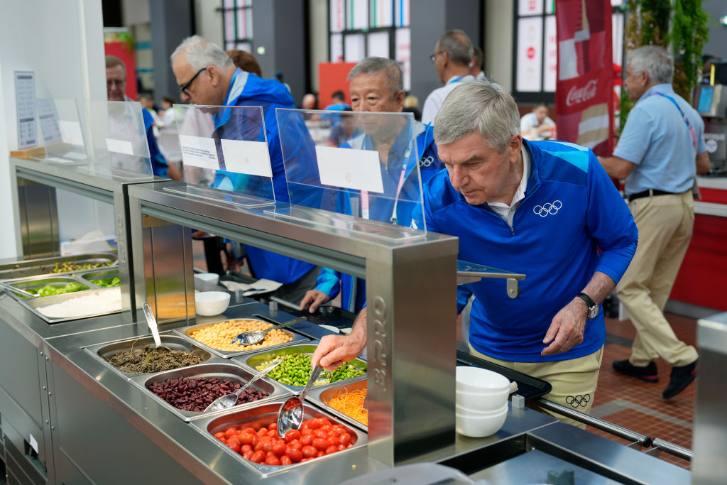 International Olympic Committee President Thomas Bach tries food from a salad bar while touring the Olympic Village ahead of the start of the Paris 2024 Olympic Games on July 22, 2024 in Paris, France.