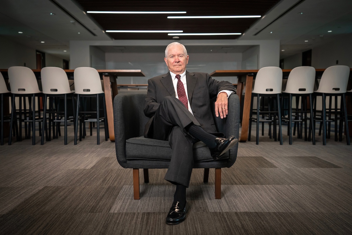 Robert Gates sits in a chair in a common area of the Bush School.