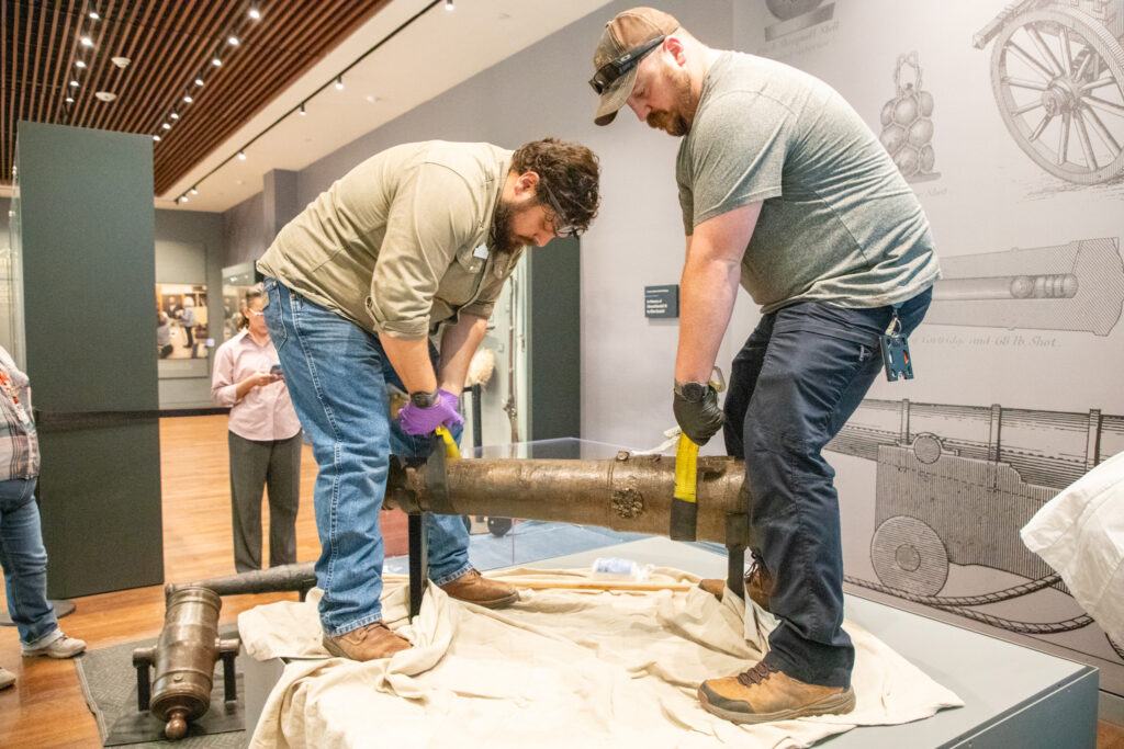 Alamo Museum staff adjust the cannon in the display area.