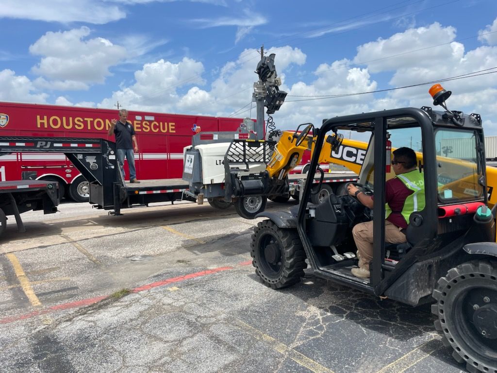 A generator is loaded onto a flatbed trailer by a forklift operator.