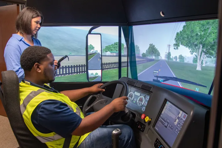 Center staff assists with truck driver training on a simulator