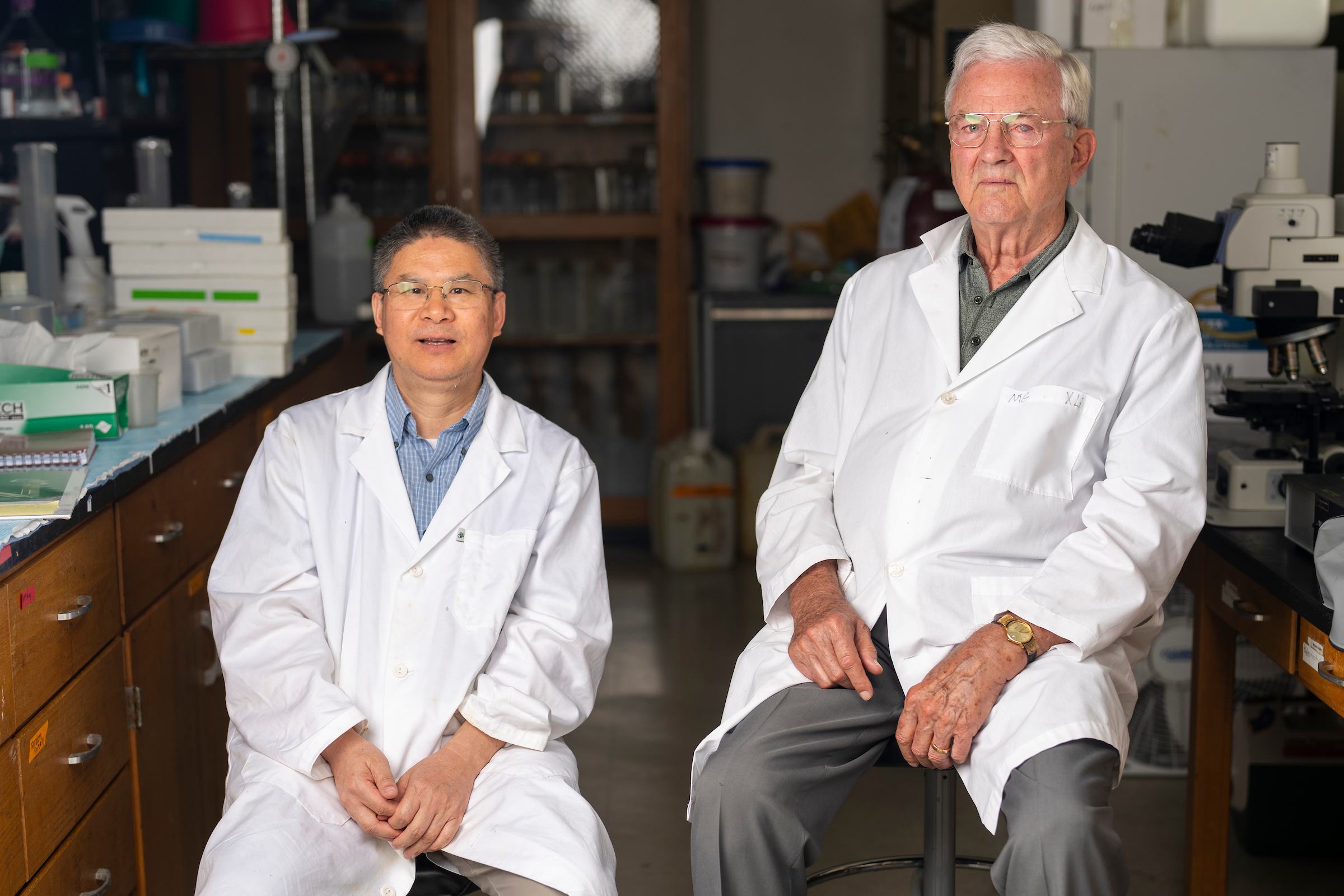 Two researchers in white coats seated in a lab