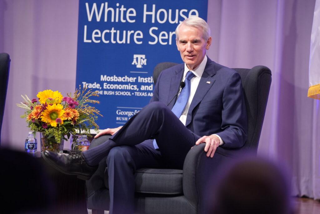A photo of former U.S. Sen. Rob Portman sitting in a chair on a stage while wearing a suit.