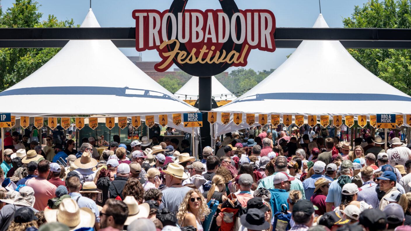 A photo of a crowd of people under a sign that says Troubadour Festival.