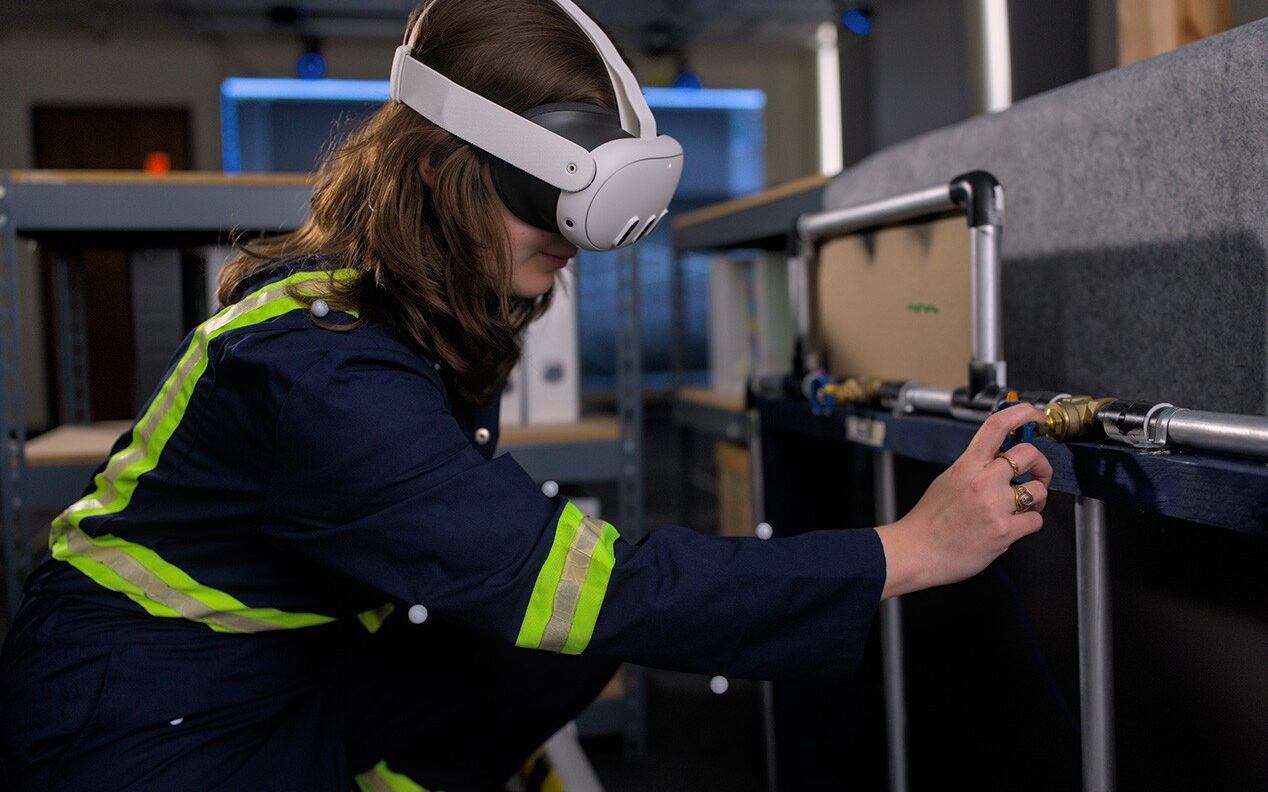 A woman wears a virtual reality headset while performing tasks in a laboratory setting.