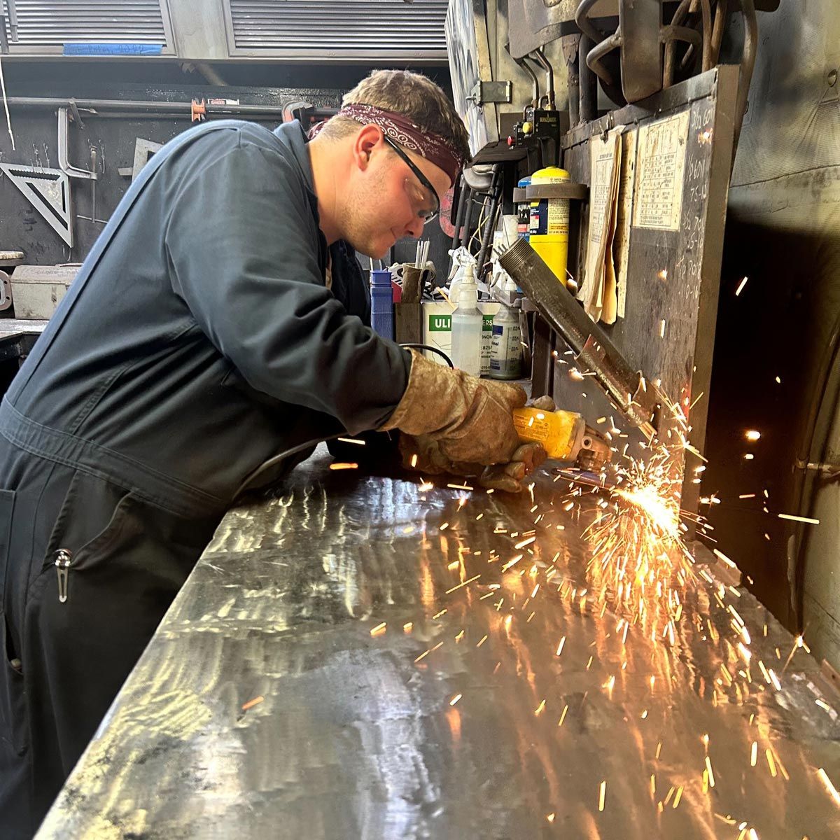 Student working with metal, causing sparks to fly in the air