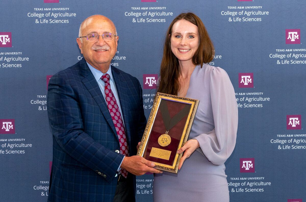 Lauren Cornell poses with the AgriLife vice chancellor with a framed medal