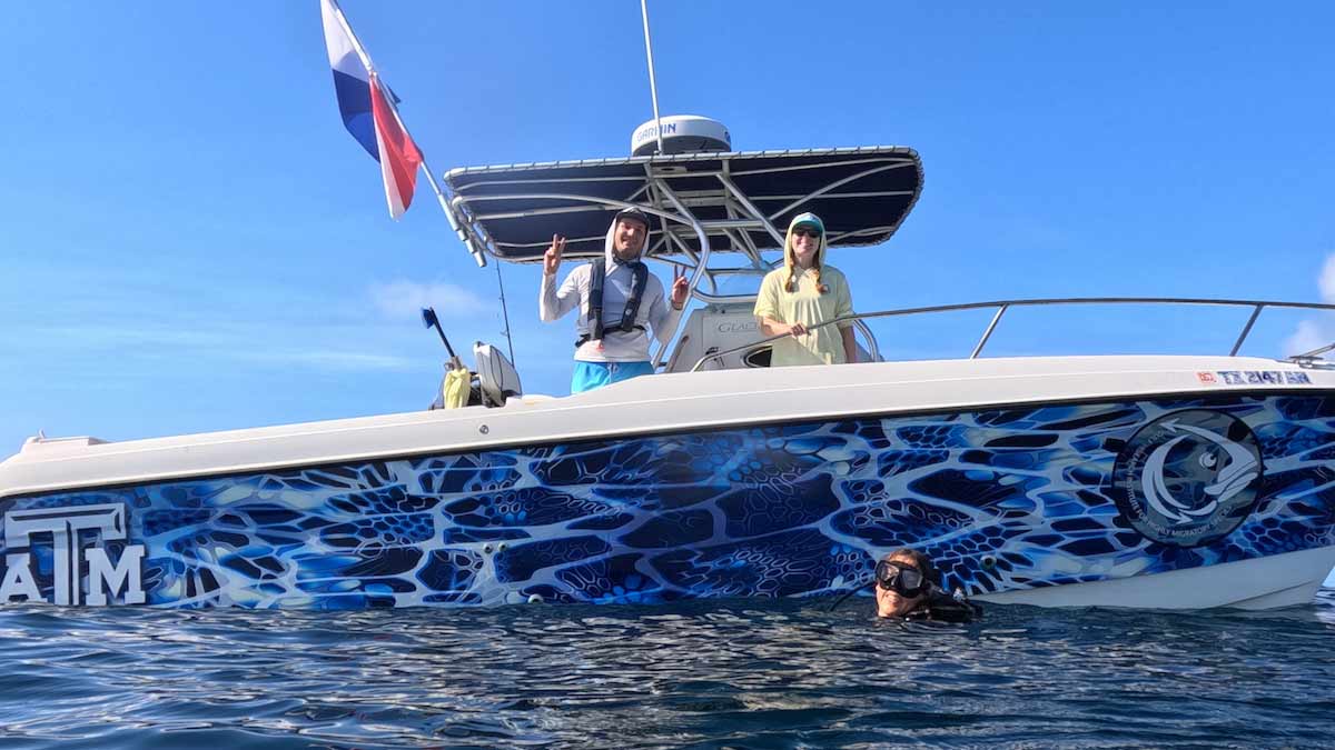 Texas A&M researchers pose on a boat next to a scuba diver