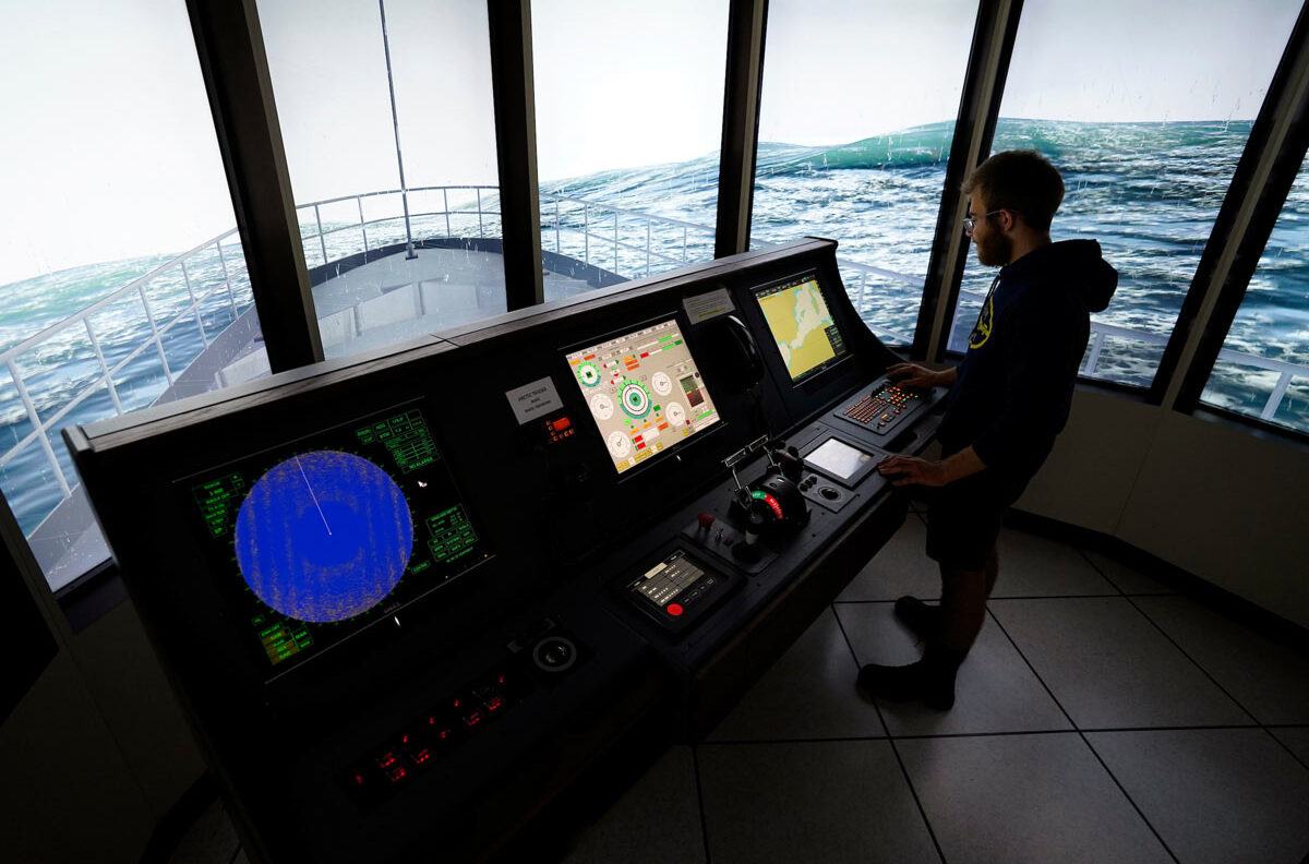 A student stands at the controls of a virtual ship