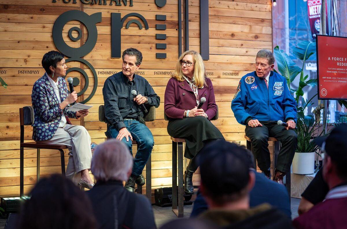 Three panelists and a moderator have a discussion on stage at the Fast Company Grill