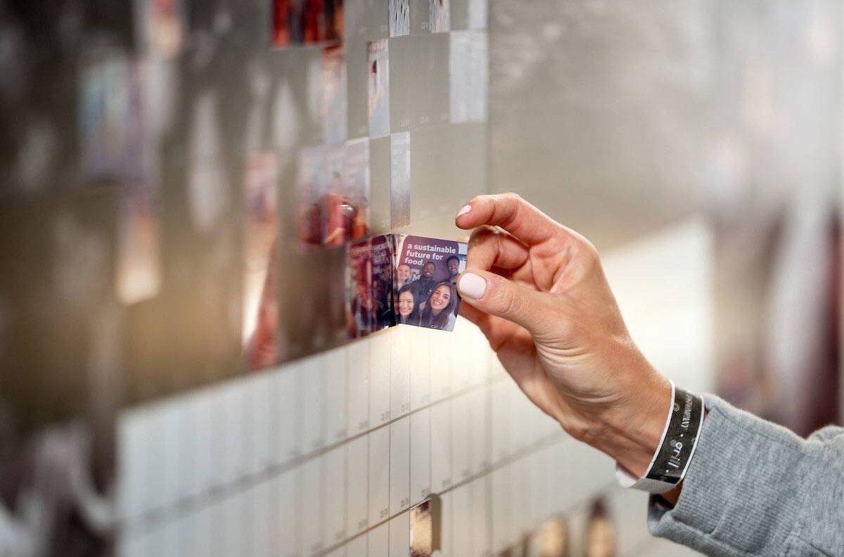 Close up of a hand adding a small selfie print out to the mural