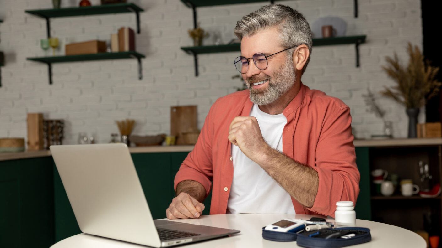 A photo of a man interacting with a laptop computer while seated at a table.