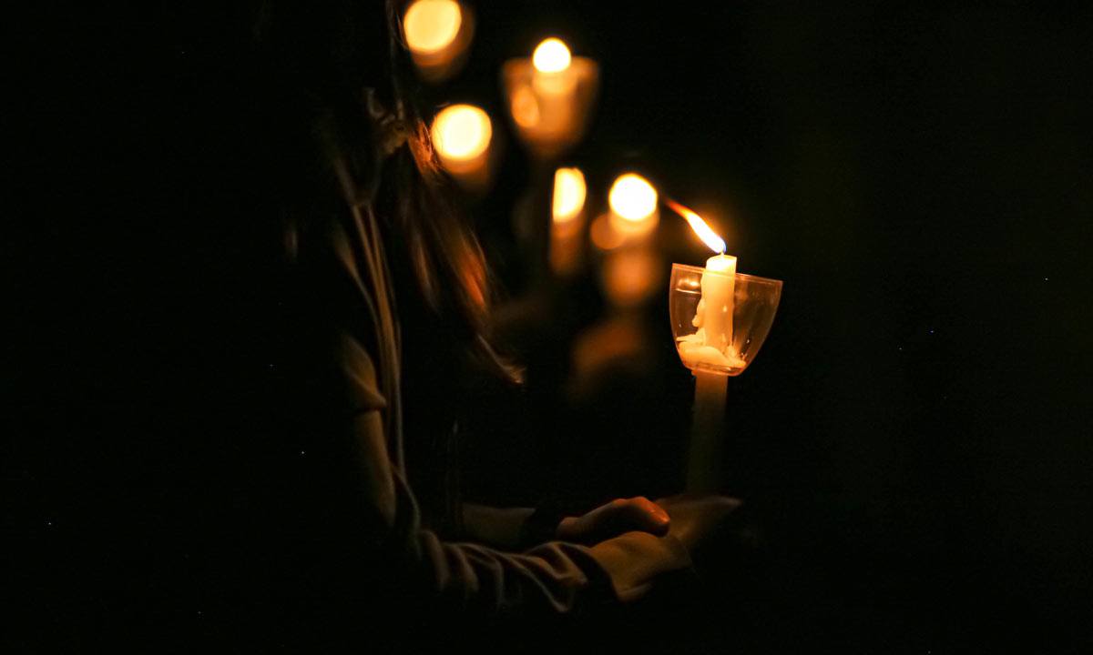 Close up on a long tapered candle lit during the Muster ceremony