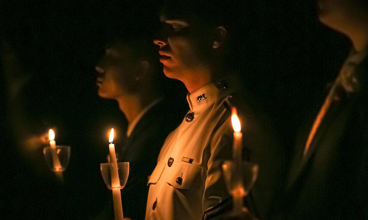 Cadet softly illuminated by holding a candle during a Muster ceremony