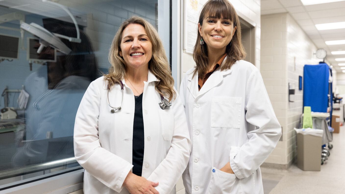 A photo of two researchers in lab coats standing in a lab.