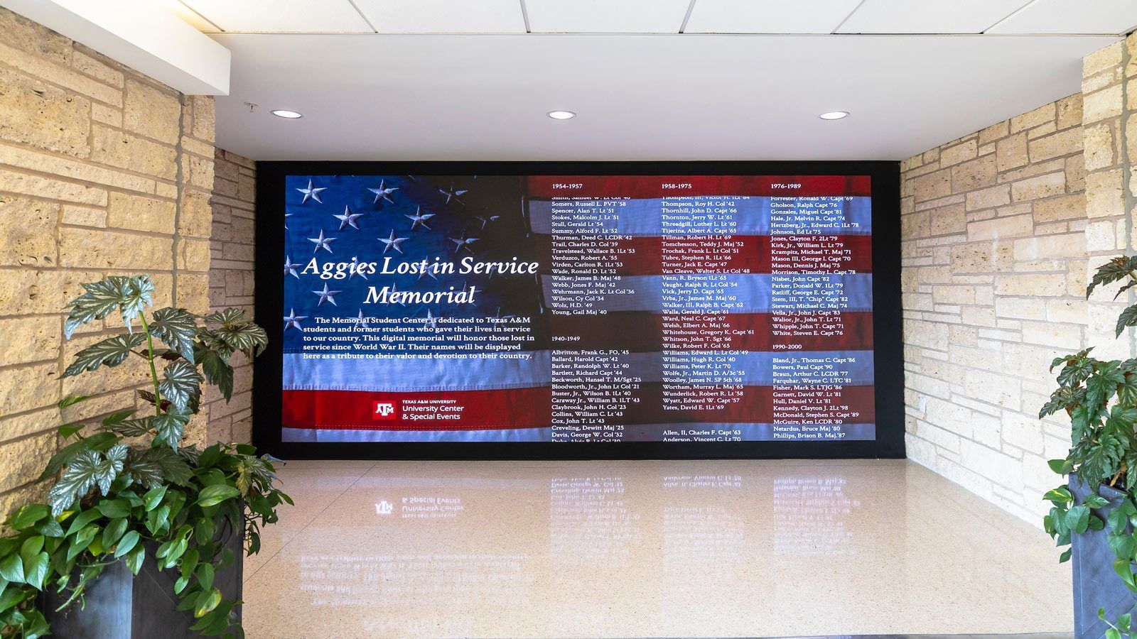 Large screen showing scrolling names of Aggies lost in service over an American flag.