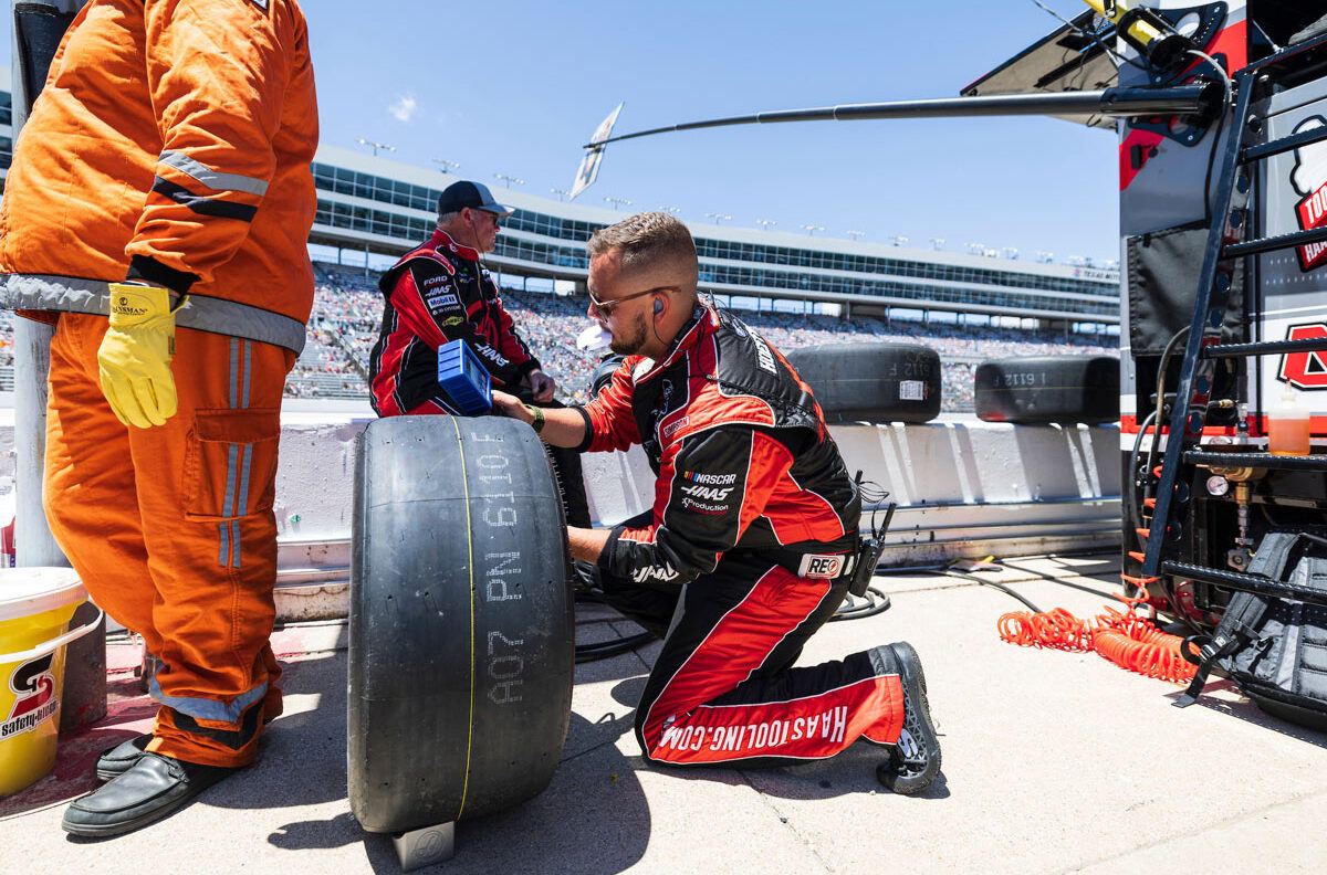 A pit crew member handles a replacement tire