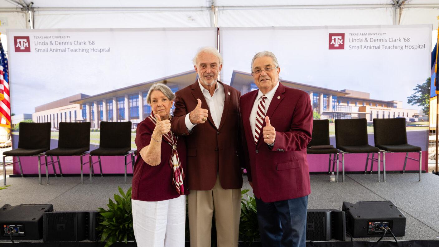 A photo of three people standing in front of an empty stage during a groundbreaking event.