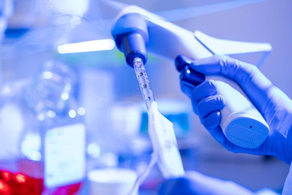 Closeup of a gloved hand using medical research equipment