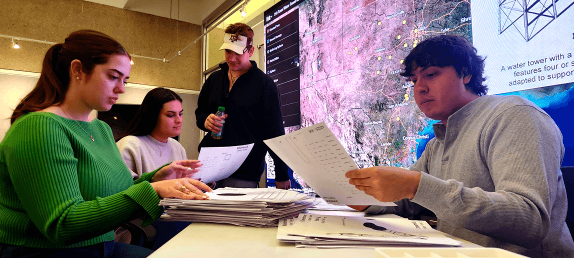 A photo of students reviewing paperwork during a class project related to water towers.