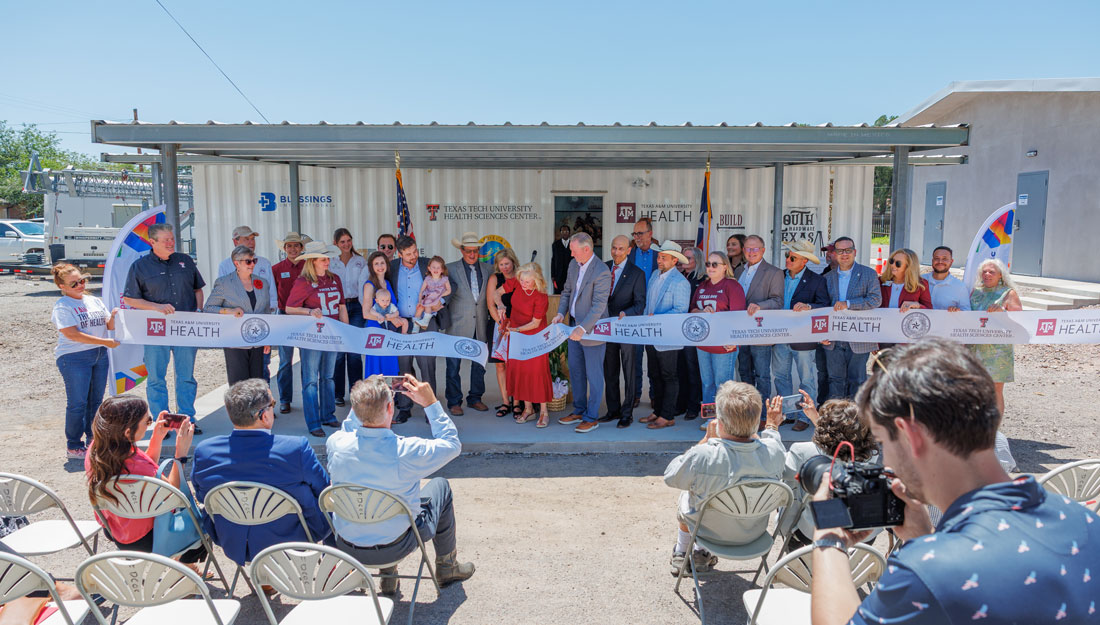 Collection of people cutting a ribbon to open a new medical clinic made out of a shipping container