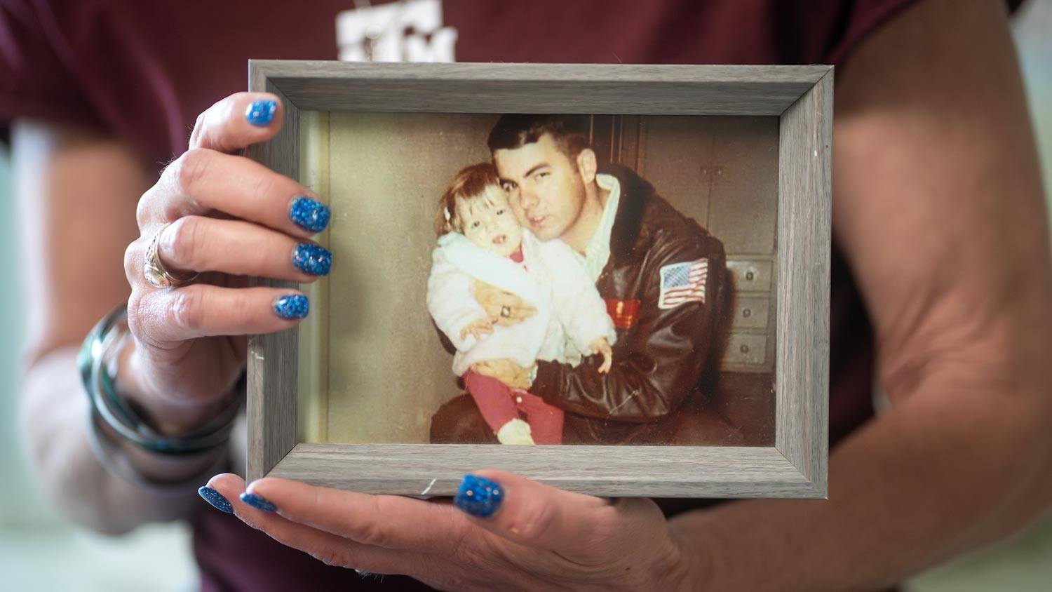 Karoni Forrester holds a framed photograph of her as a toddler with her father.